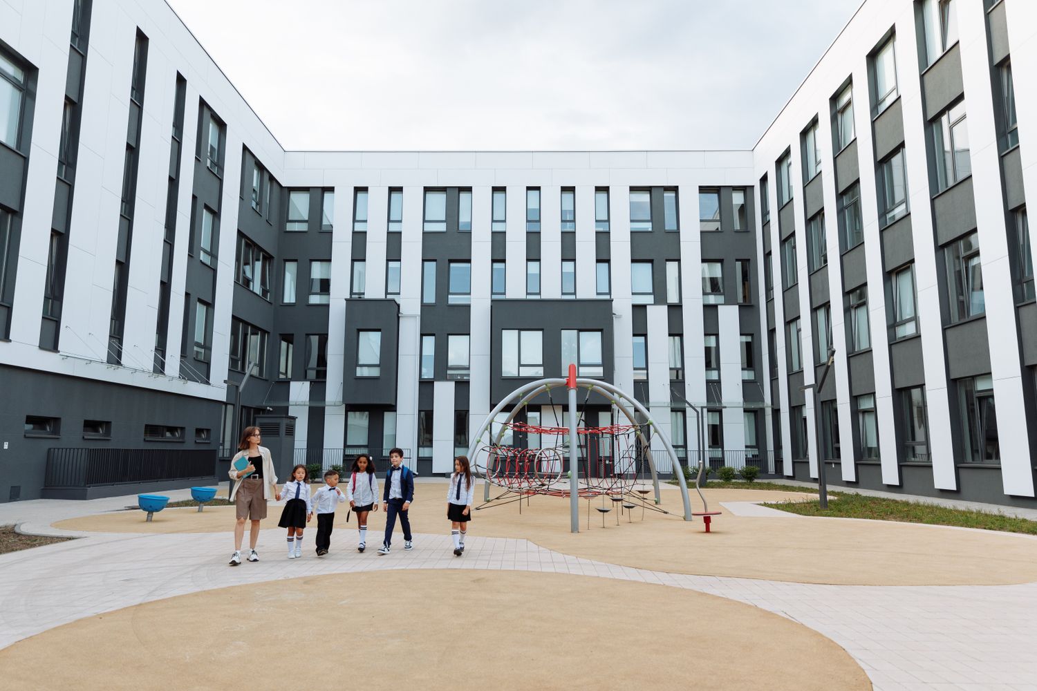 Teacher and students walking across a modern school campus